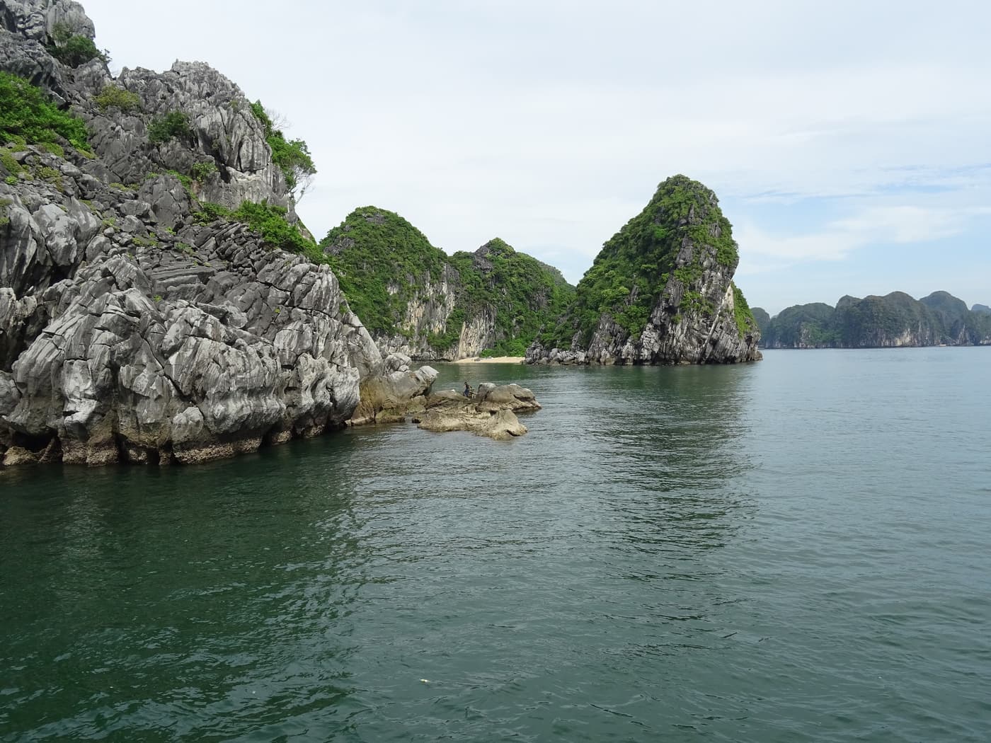 Green karst islands and calm water seen from a boat in Lan Ha Bay