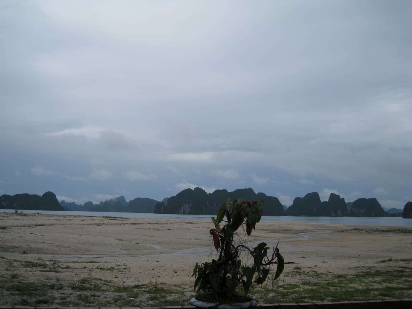 A wide sandy beach on Quan Lan island with karst islands on the horizon
