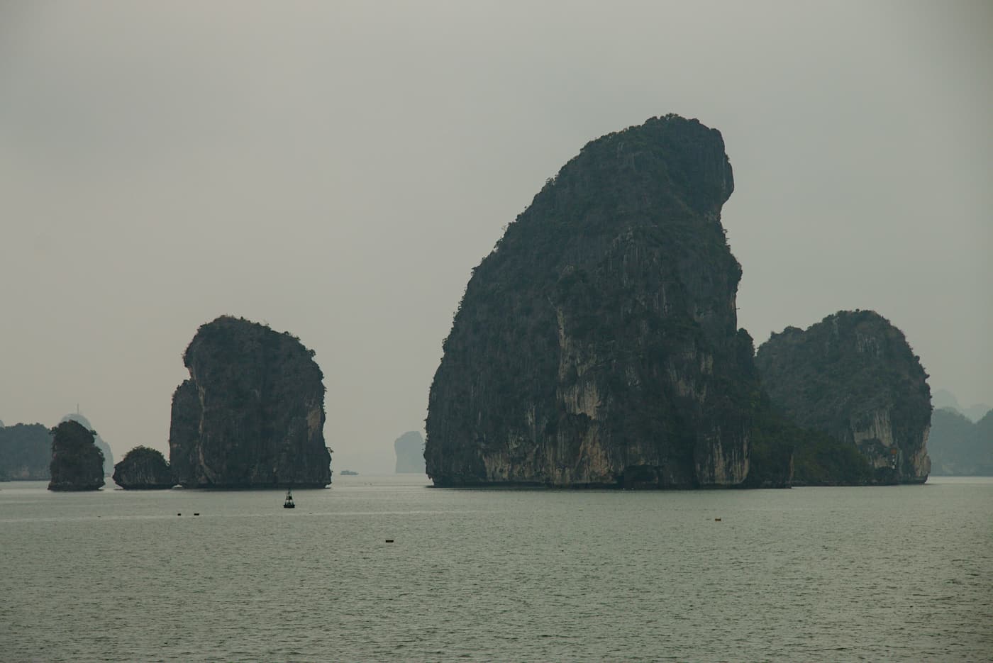 Tall limestone karsts rising from calm water in Bai Tu Long Bay