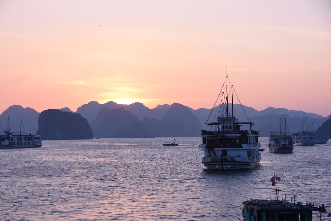 Cruise boats anchored among limestone karsts at sunset