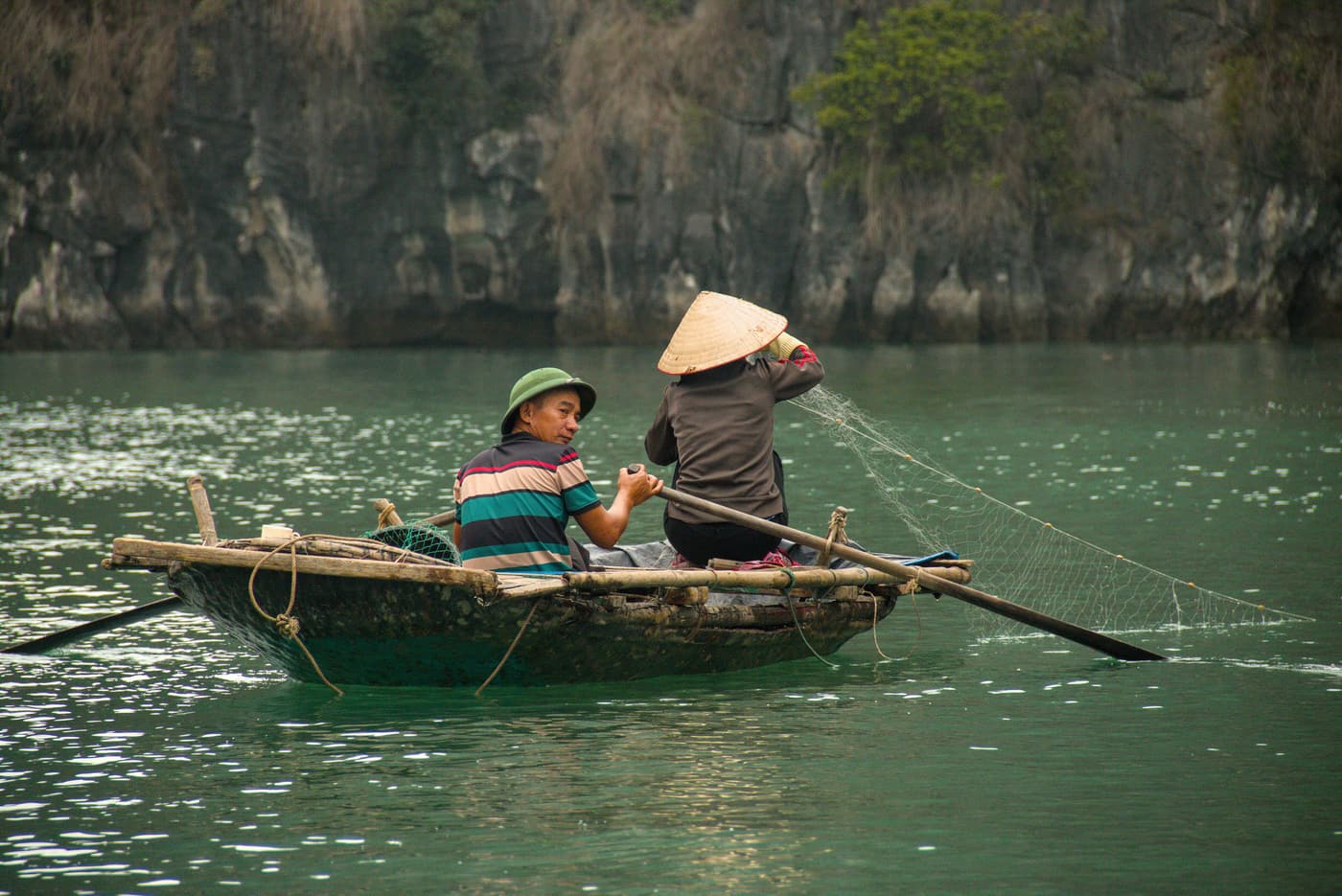 Fishermen hauling a net from a small rowing boat in Bai Tu Long Bay