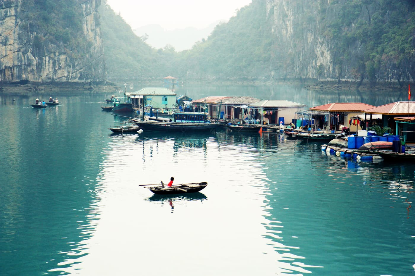 A floating fishing village with a small boat rowing past