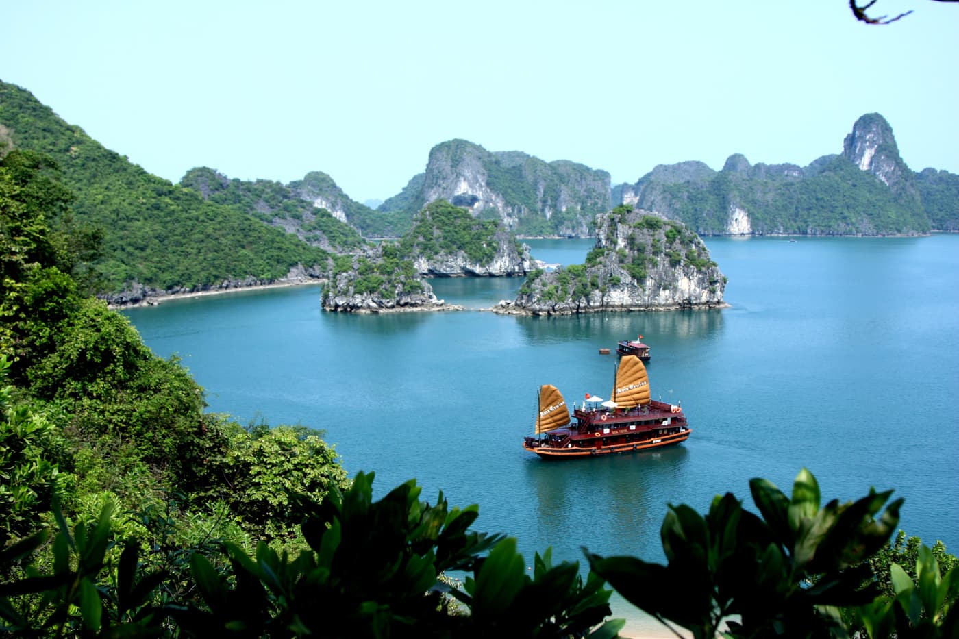 A traditional wooden junk with ochre sails cruising between karst islands