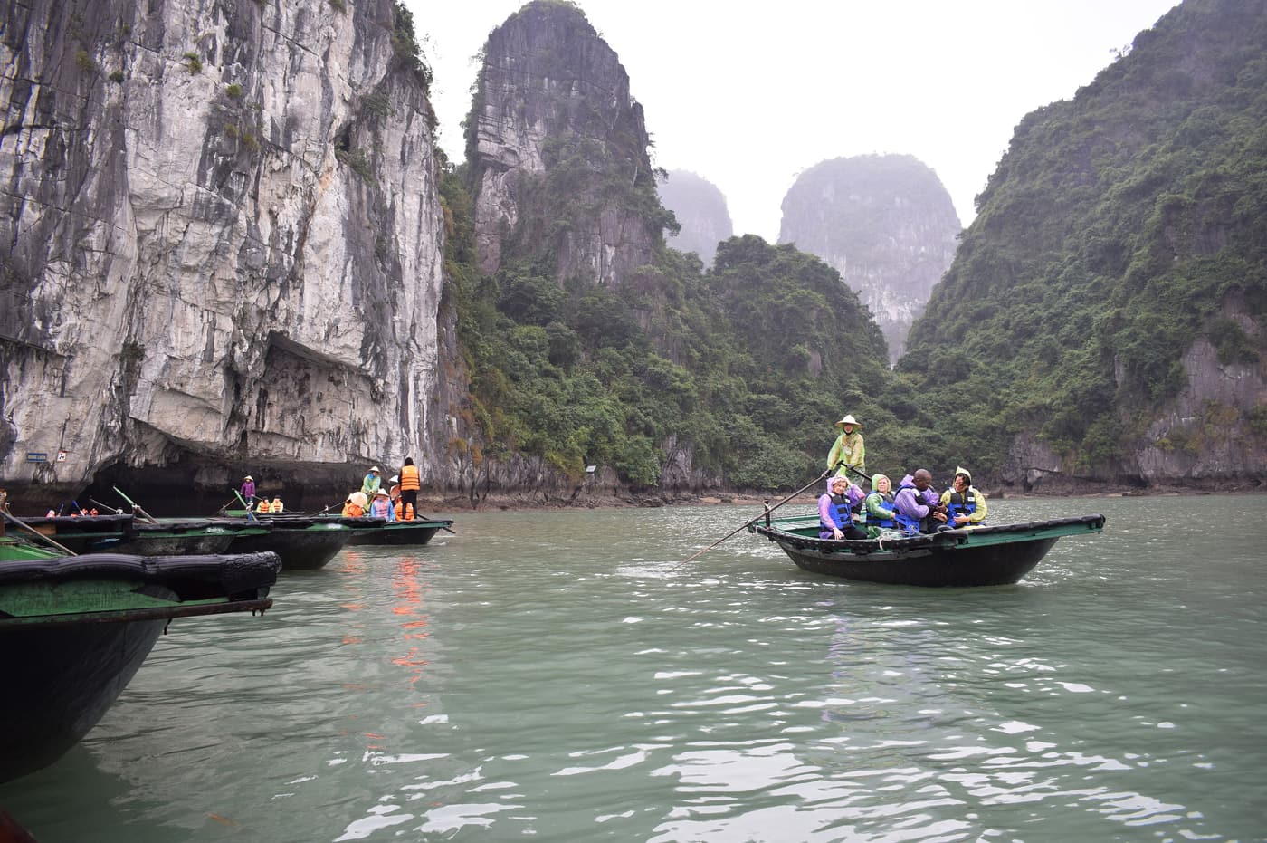 Tourists in rowing boats heading towards Luon cave in Ha Long Bay